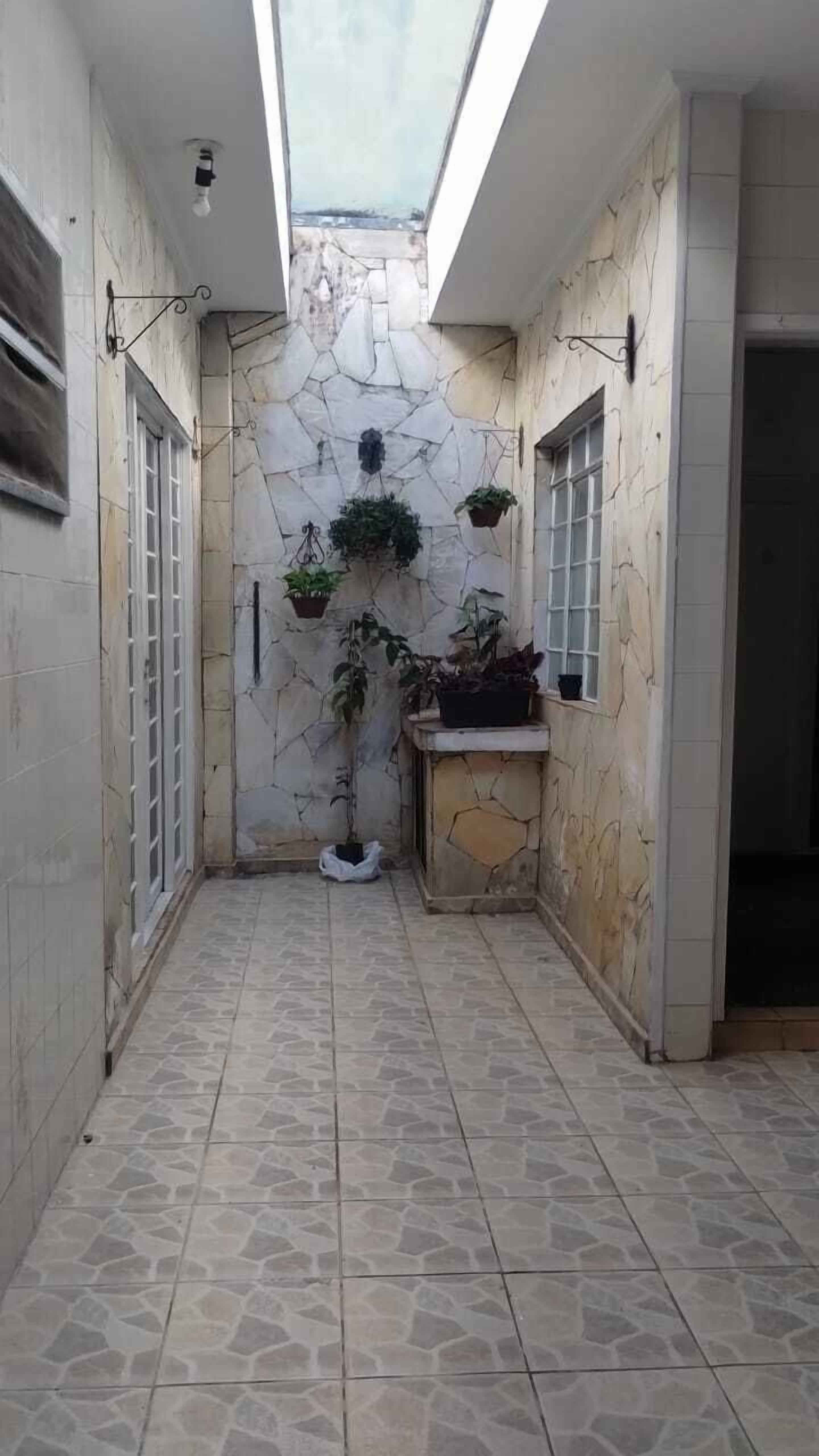 Un estrecho pasillo con paredes de piedra, un tragaluz y plantas en macetas.
