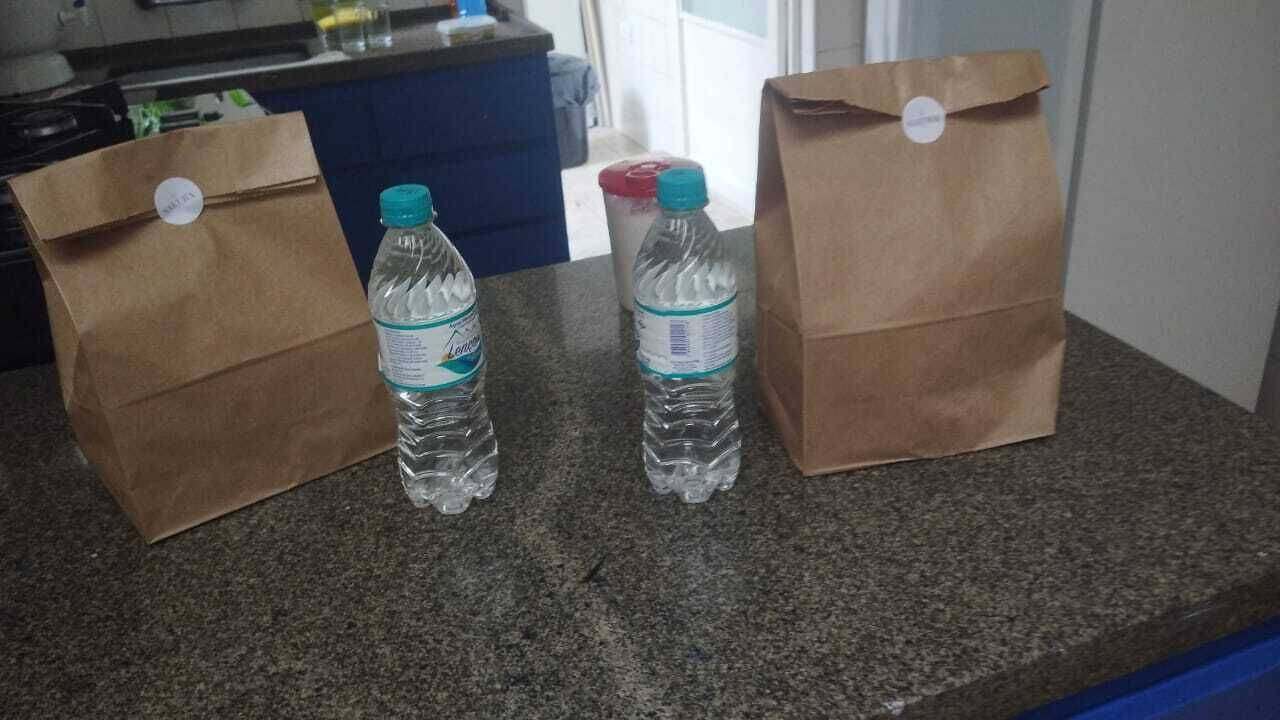 Två bruna papperspåsar står på en bänkskiva av granit, tillsammans med två vattenflaskor.