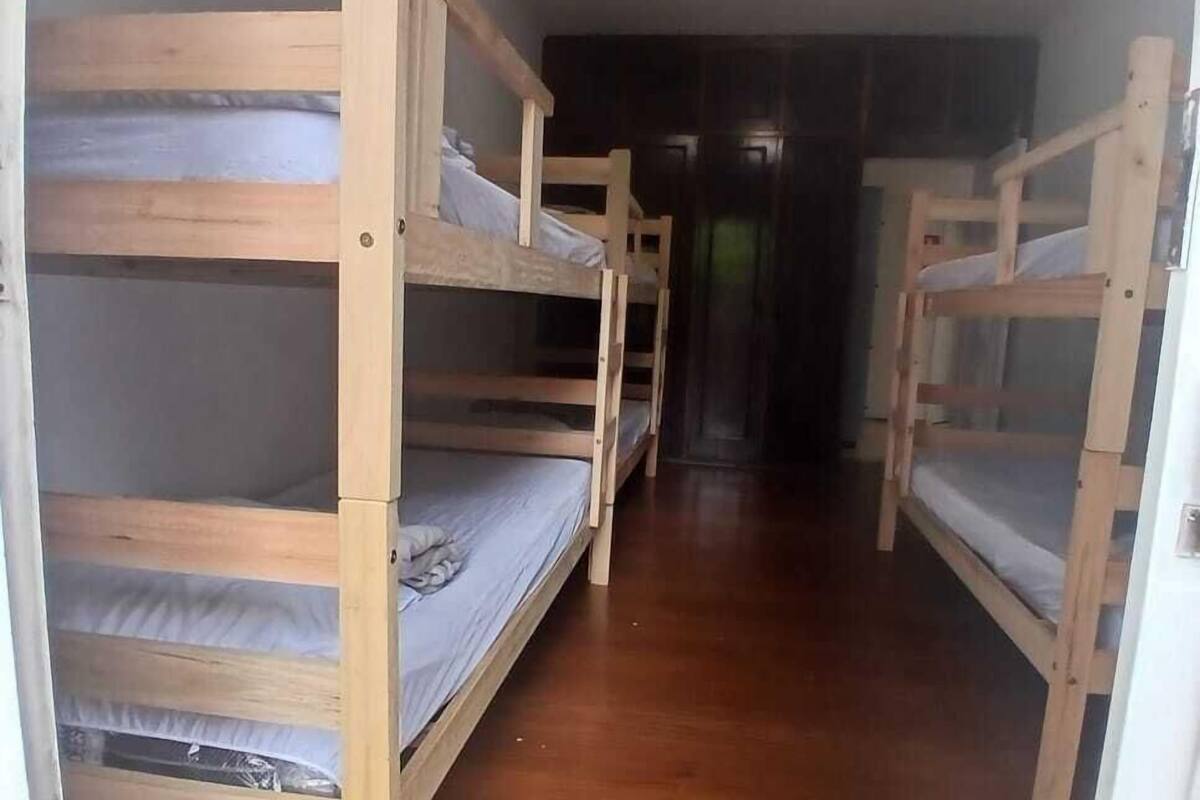 A corridor with bunk beds, wooden flooring, and a ceiling light fixture.