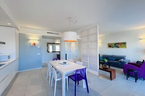 A modern living space with a dining area, a sofa, and a coffee table. - Luxury Flexrent Gardens - Abyssinia (Riccione)