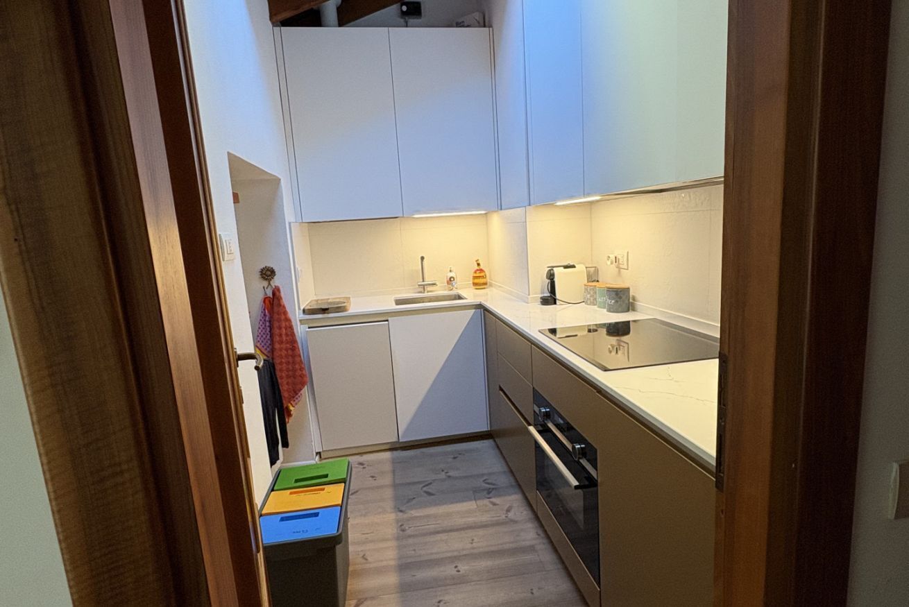 Pieni, käytännöllinen keittiö, jossa on valkoiset kaapit, työtaso ja astianpesukone.