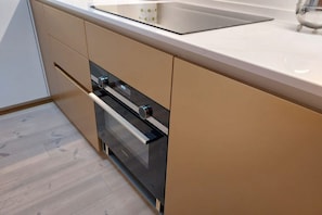 Une cuisine moderne dotée d’un four encastré, d’un évier en acier inoxydable et de meubles de couleur claire.