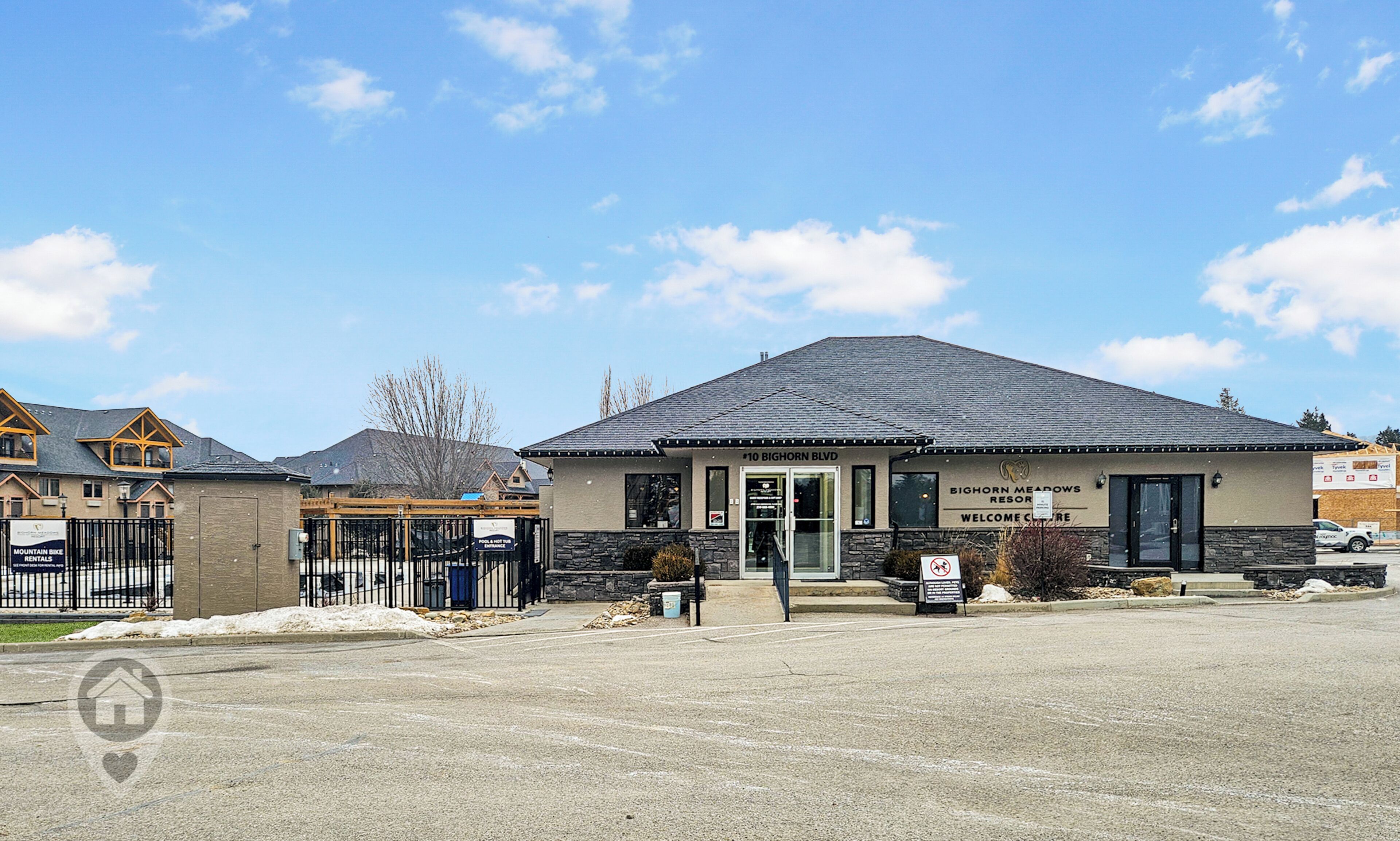 A building with a sign reading "Bighorn Meadows Resort Welcome Center" and a no smoking sign.