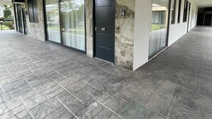 Un espacio al aire libre cubierto con un muro de piedra, una puerta negra con la etiqueta '10' y un cartel de detector de incendios.