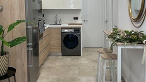 Una cocina moderna con lavadora integrada, refrigerador y pileta.
