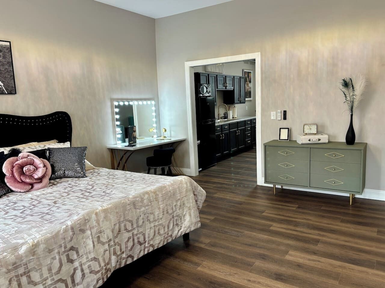 Um quarto com cama, penteadeira com espelho e cômoda.