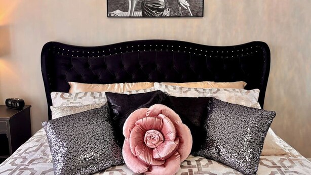 A bedroom with a tufted headboard, a large decorative pillow, and a poster of Marilyn Monroe on the wall. - Marilyn Monroe Vintage Suite (Logan)