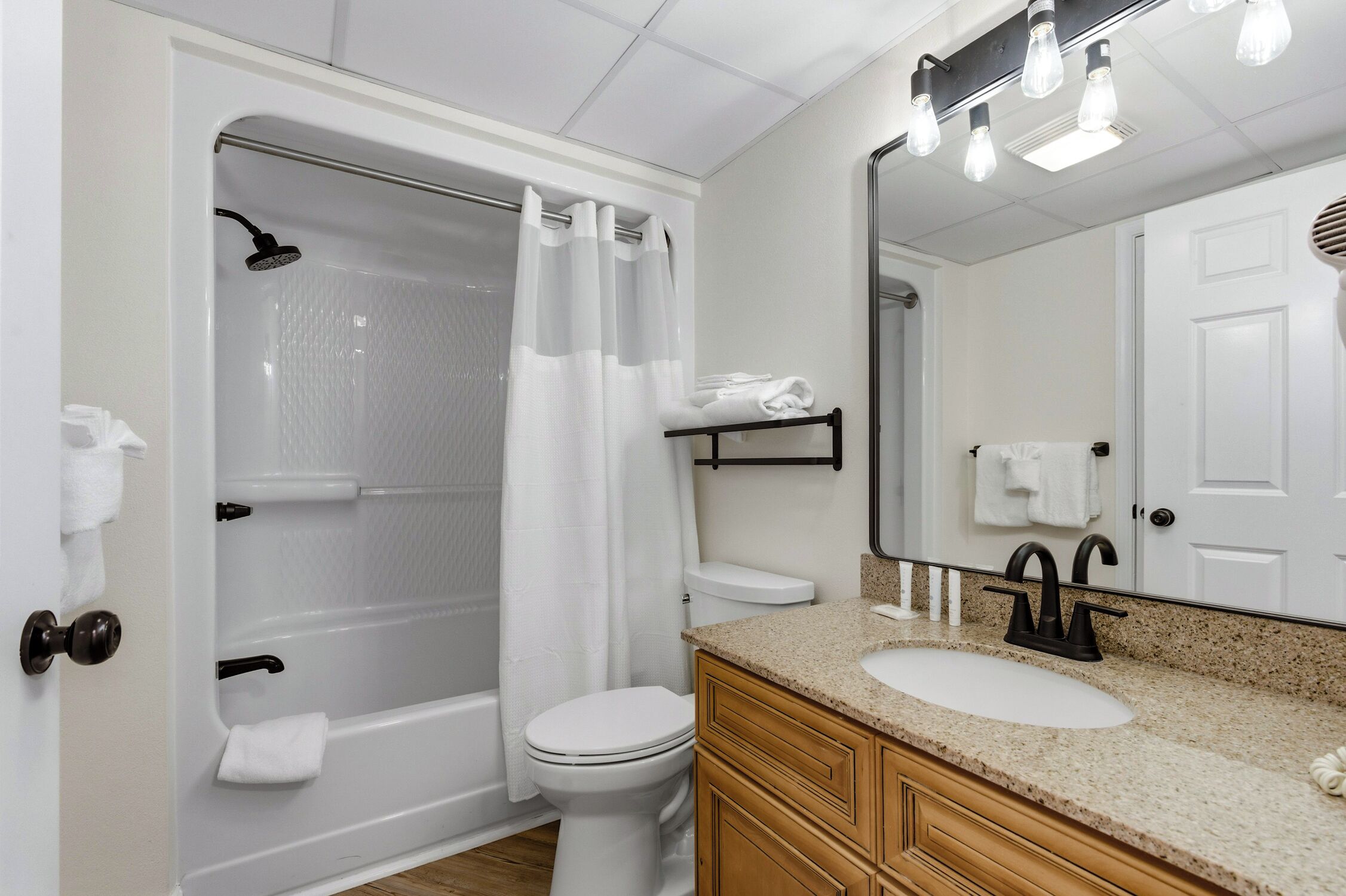 Un baño con bañera, inodoro, lavamanos y espejo.