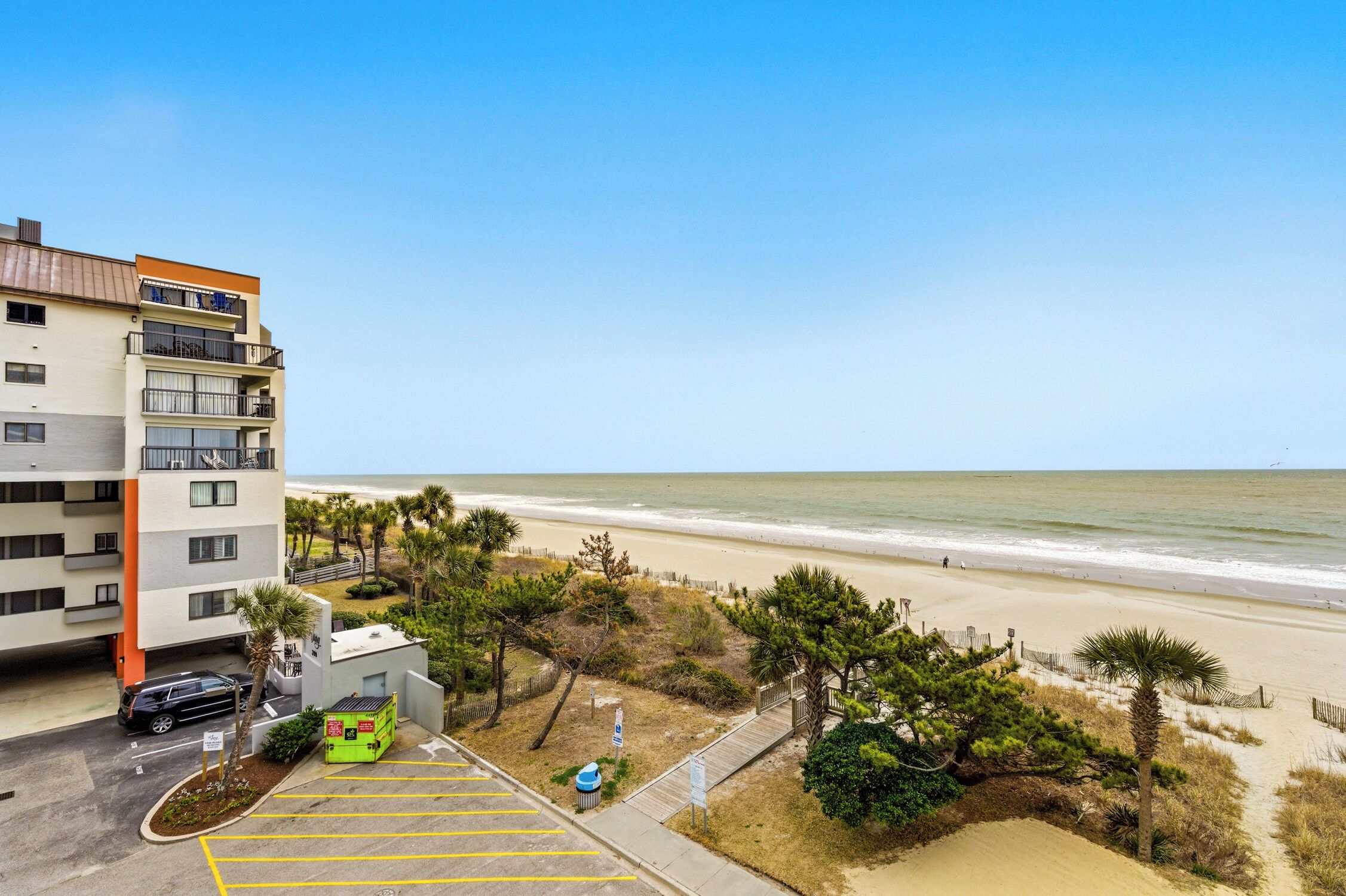 Un hôtel situé en bord de mer, doté d’un parking, offrant une vue sur la plage et comprenant un bâtiment avec de nombreux balcons.