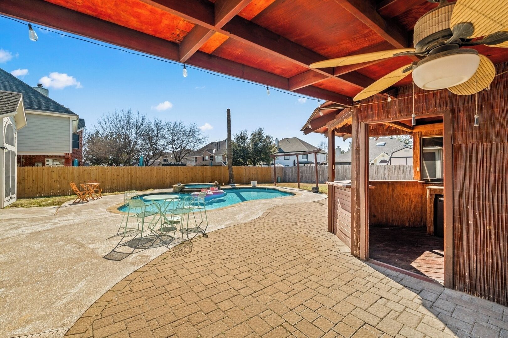 Un patio trasero con piscina, mobiliario de patio y terraza de madera.
