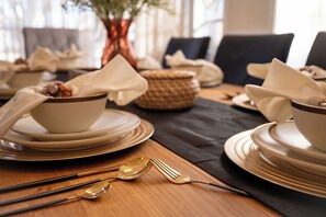 A dining table set with bowls, plates, and cutlery. - Family 4BR Retreat | Pool • BBQ • Game Room (Grand Prairie)