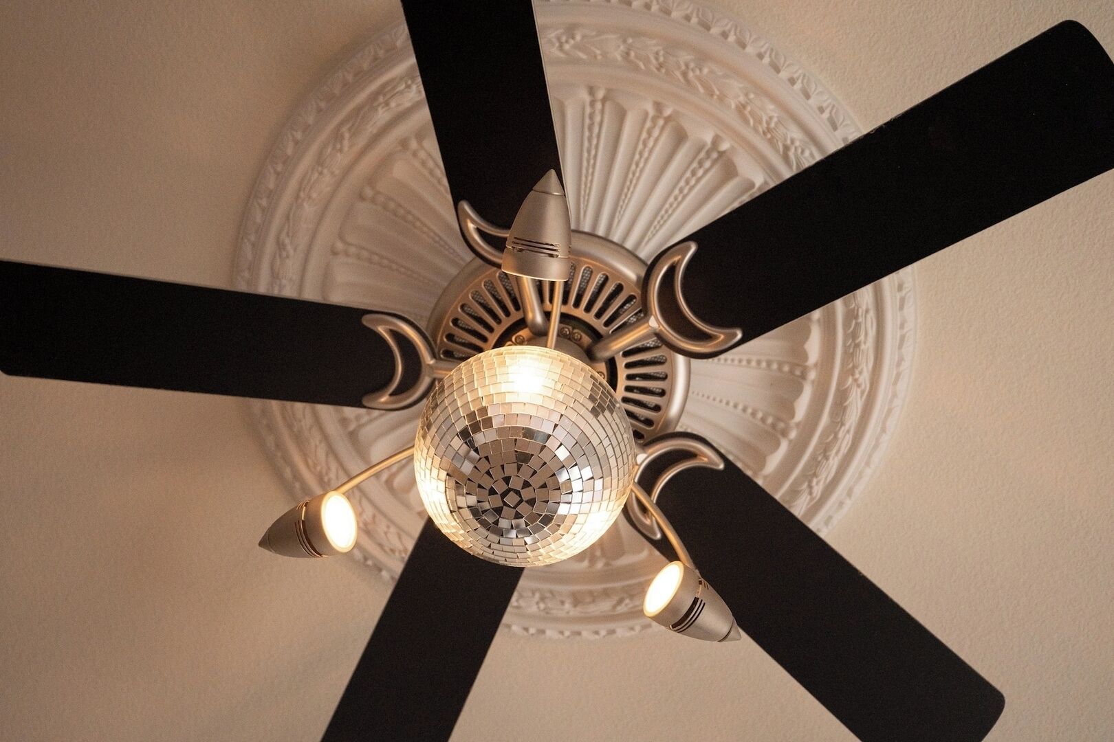A ceiling fan with a disco ball and three light fixtures.