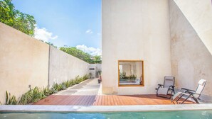 A modern outdoor pool area with a wooden deck, lounge chairs, and a view of the surrounding landscape.