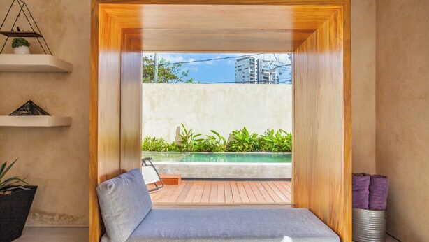 A room with a wooden-framed window seat, a small table, and a potted plant.