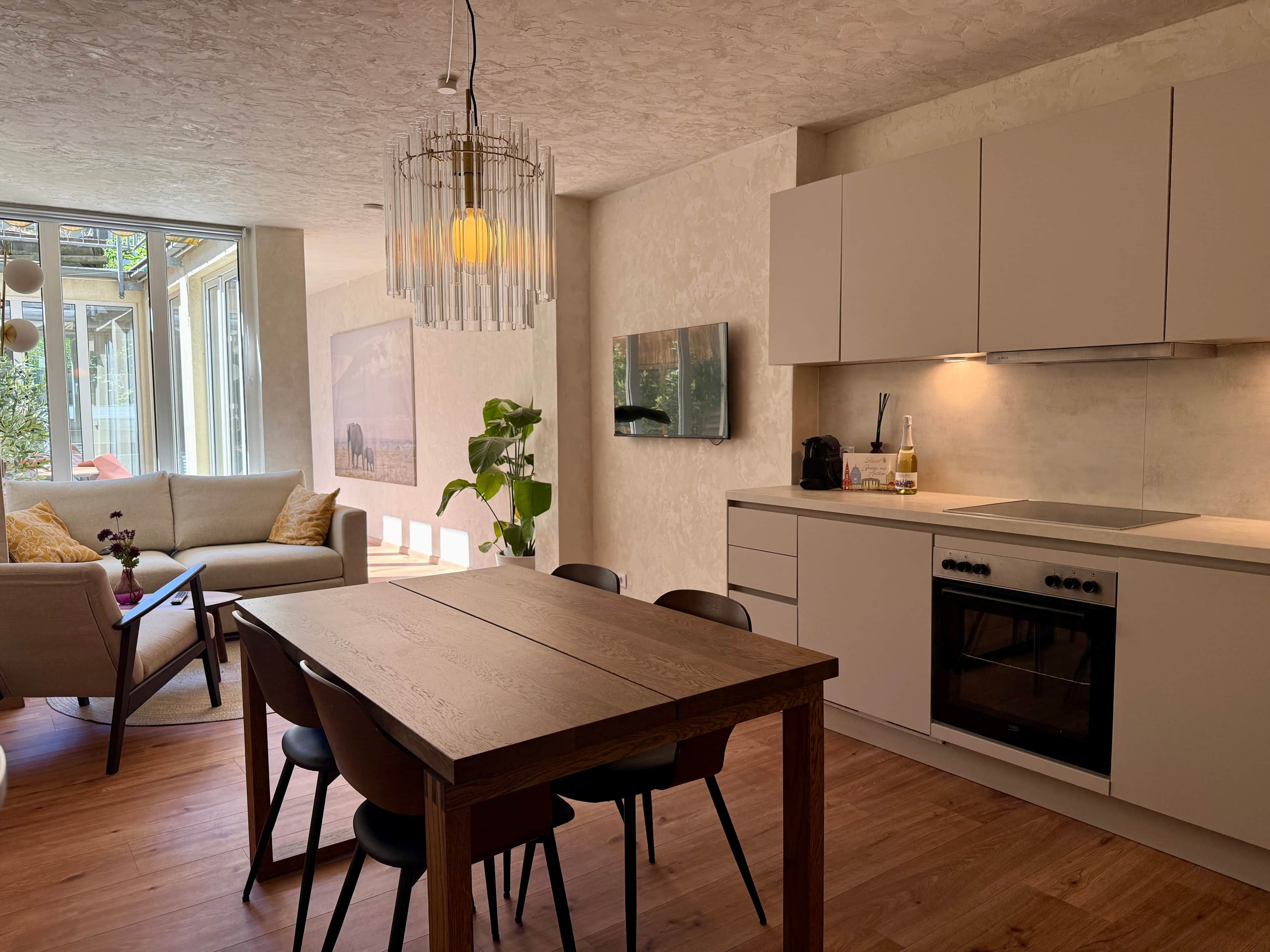 Una cucina moderna con zona pranzo, pavimento in legno e un'ampia finestra.