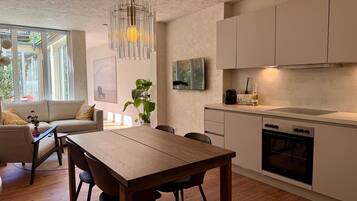 Una cucina moderna con zona pranzo, pavimento in legno e un'ampia finestra.