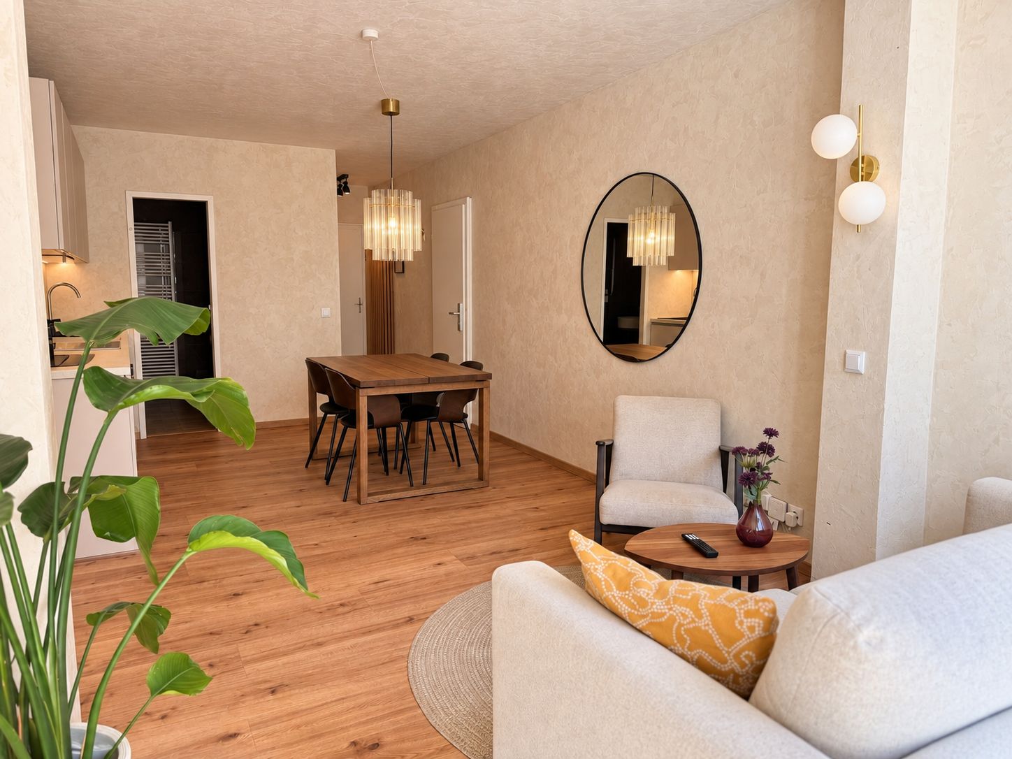 Un salon moderne comprenant un coin repas, un canapé, une table basse et une grande plante.