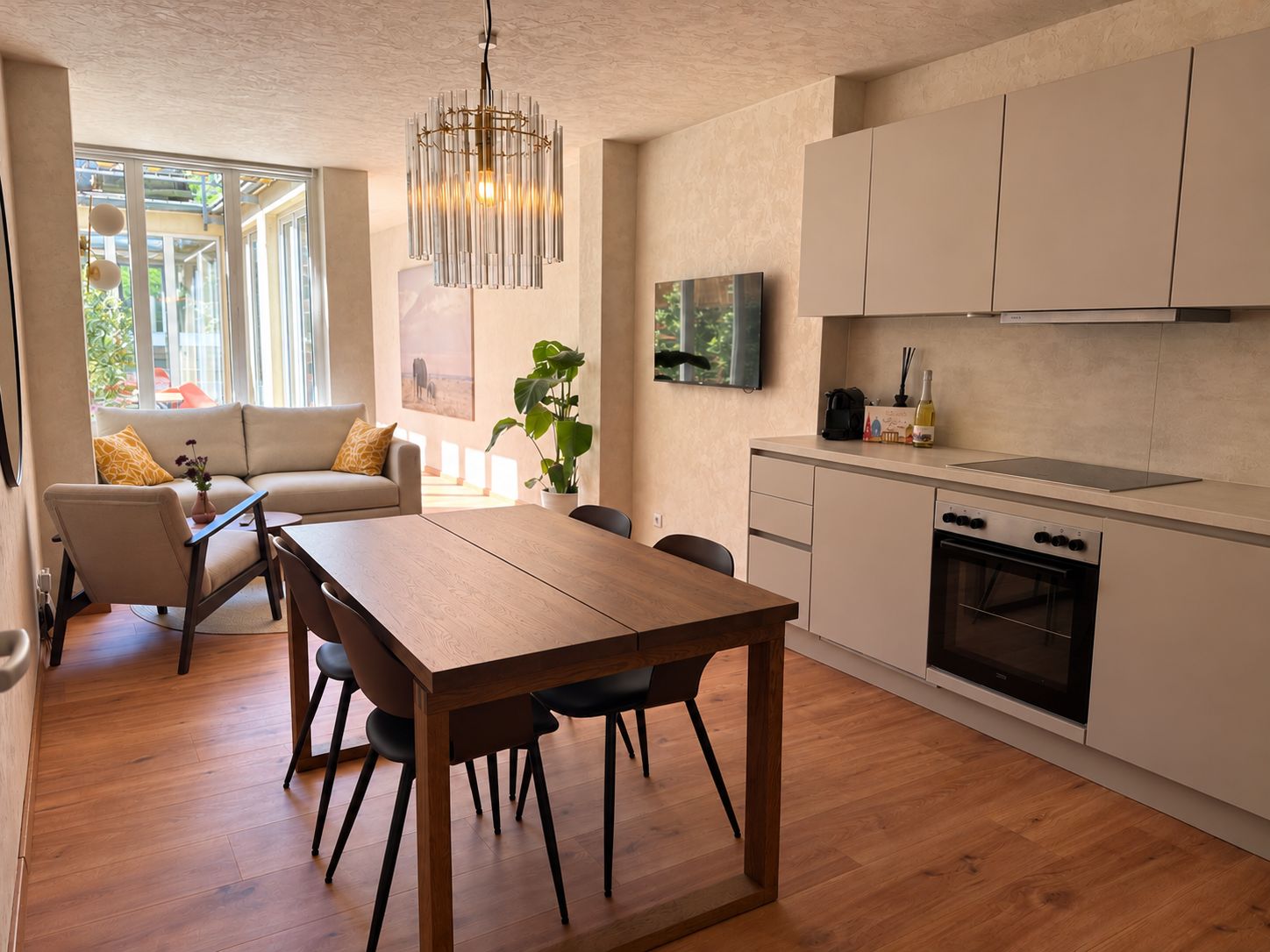 Une cuisine moderne avec un coin repas, un plancher en bois et une grande fenêtre qui laisse entrer la lumière naturelle.
