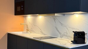 Eine moderne Küche mit dunklen Schränken, einer Marmorarbeitsplatte und einem eingebauten Backofen.