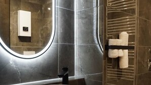 A modern bathroom with a round sink, a large mirror with integrated lighting, and a towel rack. - Atrium Apartments Aachen 1 (Aachen)