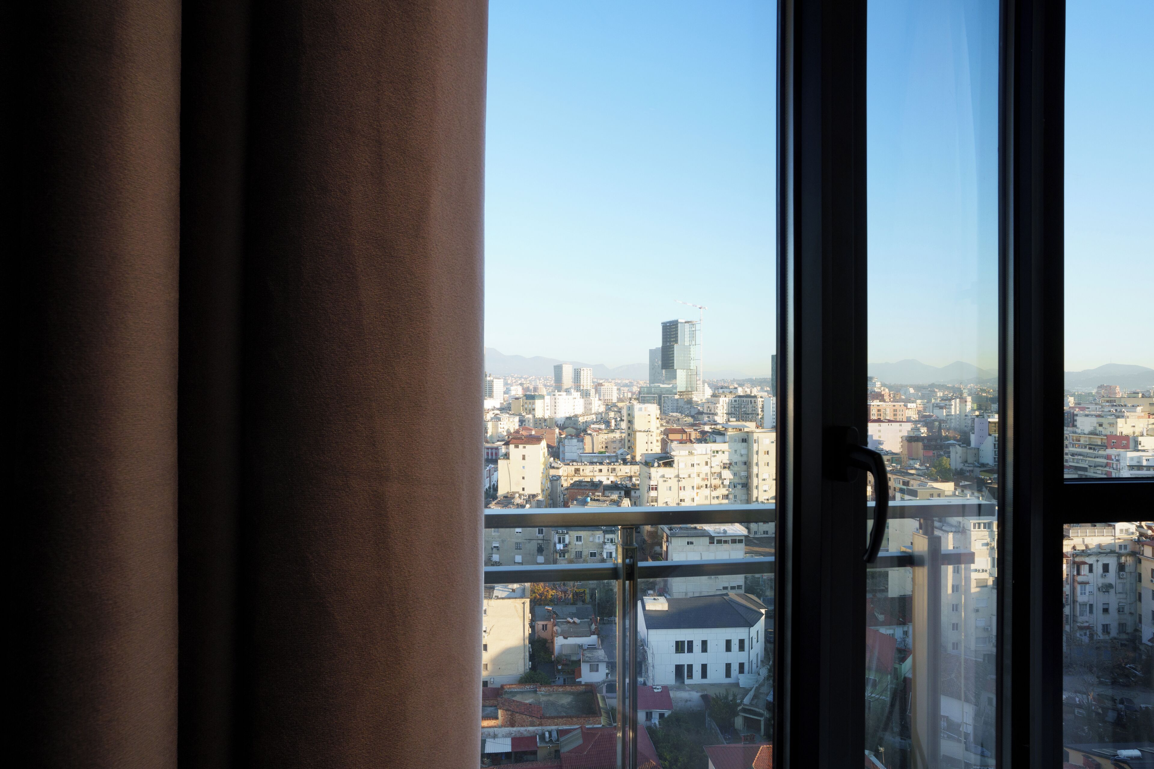 A cityscape through a window with a view of buildings and a clear sky.