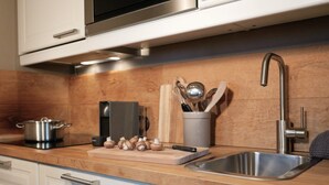 A modern kitchen with stainless steel appliances, a wooden countertop, and a built-in sink. - The small apartment (23 square meters) in a modern country house style (Reit im Winkl)