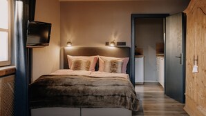 A bedroom with a bed, two bedside lamps, a television, and a wooden wardrobe. - The small apartment (23 square meters) in a modern country house style (Reit im Winkl)
