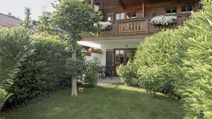 A wooden building with a balcony, surrounded by well-maintained hedges and a lawn. - The small apartment (23 square meters) in a modern country house style (Reit im Winkl)