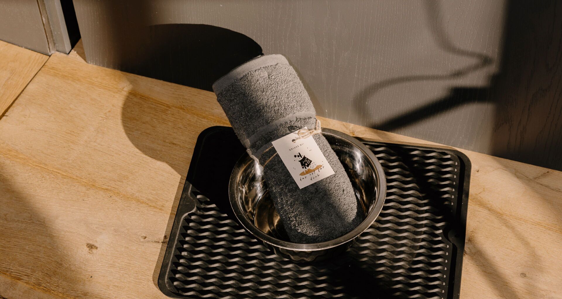 A metal bowl with a black textured cloth inside, placed on a textured mat.