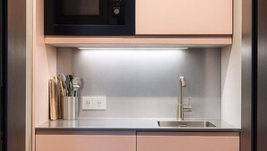 A modern kitchen with a stainless steel sink, a microwave above the countertop, and a utensil holder on the left. - The newly renovated apartment (30 m²) has a combined living and sleeping area (Reit im Winkl)