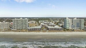 Een kuststadsbeeld met hoge gebouwen, een strand en golven in de oceaan.