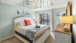 Een slaapkamer met dakraam, een bed met bloemenbedrukking, een nachtkastje met lamp en uitzicht op buiten via een schuifdeur.