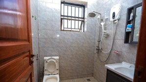 Een kleine badkamer met toilet, douche en wastafel.