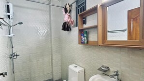 Een badkamer met douche, toilet en wastafel.