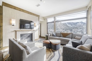 A modern living room with a fireplace, a flat-screen TV, and a sofa set. - Charlie Rentz: Riverfront Resort/Spa, Ski-In/Out, Private Deck, Mountain Views, Remodeled #821 (Avon)