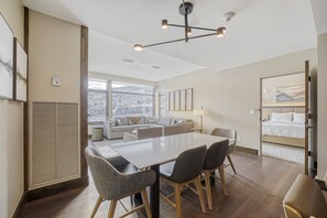 Una habitació d'hotel moderna amb un gran finestral, una zona de menjador amb taula i cadires, un seient i un llit.