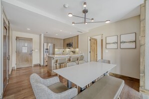 A modern kitchen with a central island, stainless steel appliances, and a dining area with a large table and chairs. - 2BR ski-in/out condo with mountain and pool views in Avon. (Avon)