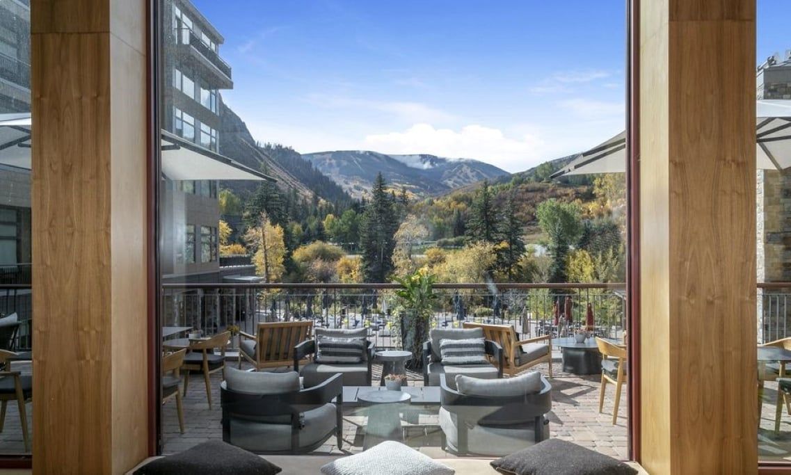 A balcony with outdoor seating, a mountain view, and a glass wall.