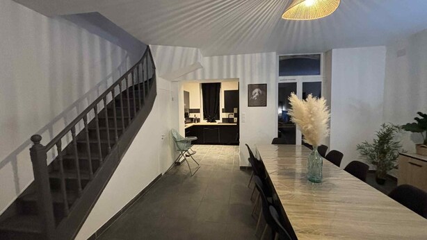 Ein modernes Interieur mit Essbereich, Treppe und einer Küche im Hintergrund.