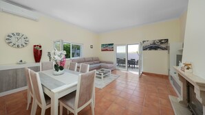 A spacious living area with a dining table, chairs, a sofa, and a fireplace. - Casa Sun Zen – 4-Bedroom Villa with Pool and Snooker Table (Mexilhoeira Grande)