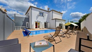 A residential property with a swimming pool, outdoor seating, and a white building. - Casa Sun Zen – 4-Bedroom Villa with Pool and Snooker Table (Mexilhoeira Grande)