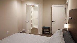 Ein Schlafzimmer mit einem Bett, einem Nachttisch, einem Hocker und einem Kleiderschrank.