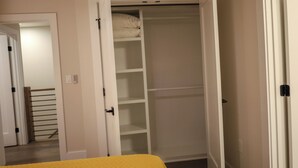 Ein begehbarer Kleiderschrank mit geöffneten Türen, der Regale und eine Kleiderstange zeigt.