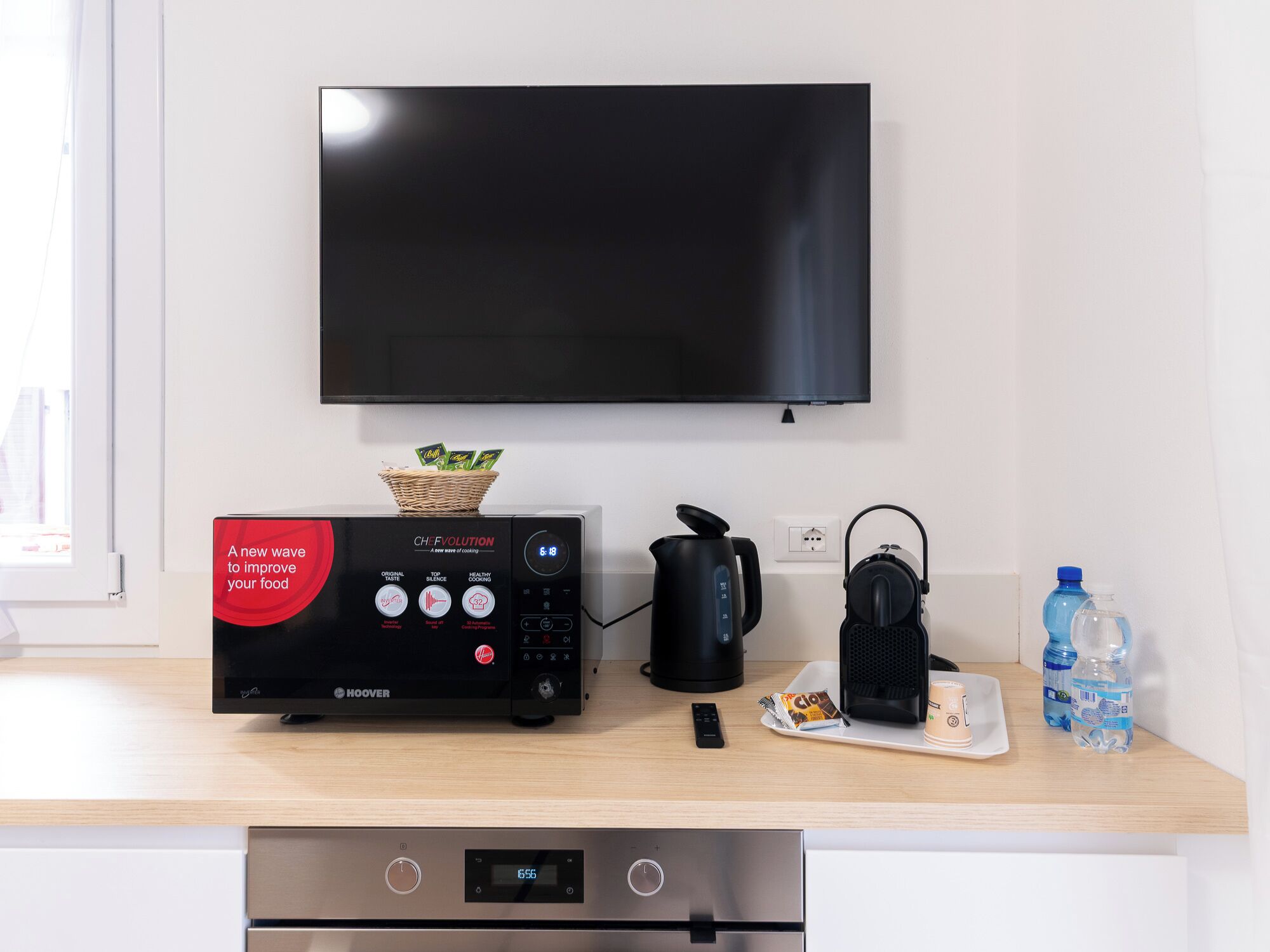 Una cocina moderna con microondas, hervidor y cafetera sobre la encimera.