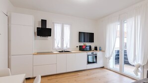 A modern kitchen with white cabinets, a built-in oven, and a flat-screen TV. - GINO SUITES - Bilocali Luxury - Appartamenti vicini a Rho Fiera e Milano (Bollate)