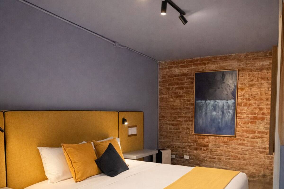 Un dormitorio moderno con una cama grande, pared de ladrillo y un cuadro.