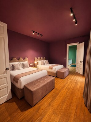 Une chambre avec deux lits, un plancher en bois et une porte donnant sur une autre pièce.
