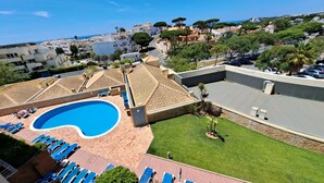 A swimming pool with lounge chairs, a grassy area, and a view of the surrounding buildings. - Apartment 'Charming Ocean View' with Sea View, Wi-Fi and Air Conditioning (Albufeira)