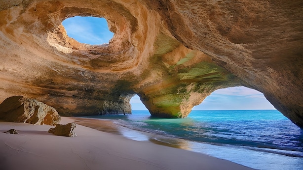 A natural rock formation with a circular opening, a sandy beach, and a view of the sea. - Solmar Garden View Apartment: Pool, Wi-Fi & Air Conditioning (Albufeira)