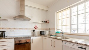 Une cuisine avec des meubles blancs, un four à micro-ondes, une cuisinière et un lave-vaisselle.